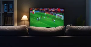 Tv passando futebol distante do sofá