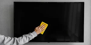 Tela de tv sendo limpa com um pano