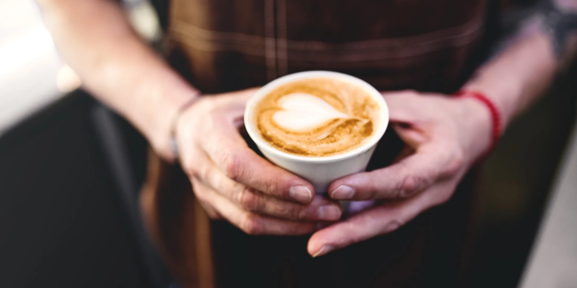 pai segurando uma xícara de café com coração na espuma de leite