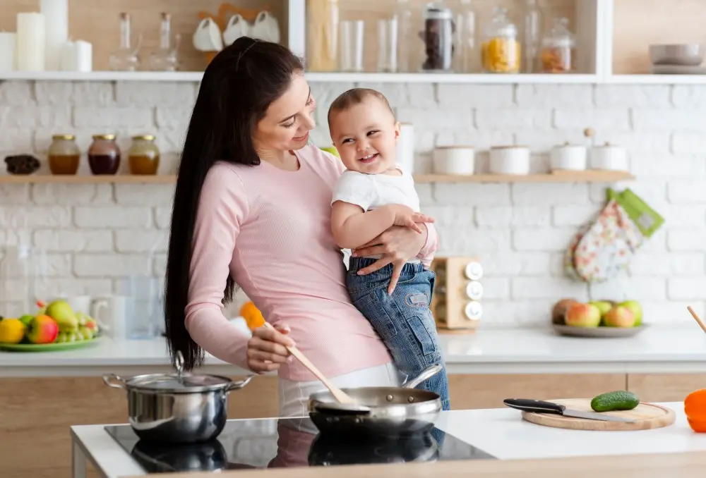 Mulher cozinhando em um cooktop com criança no colo