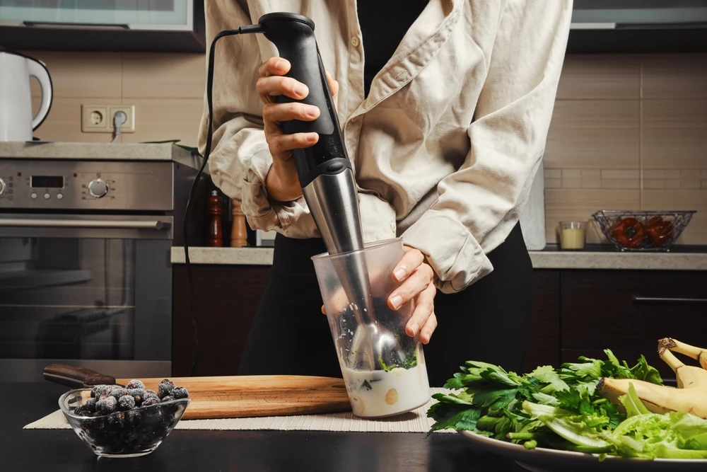 Mãos de uma mulher não identificada usando um liquidificador para fazer um smoothie.